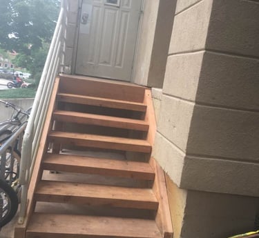 a finished wooden staircase  leading to a door with metal handrail on left side
