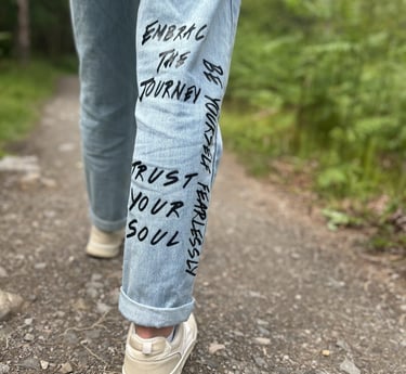 An image of someone's leg walking in nature, with empowering quotes written on the jeans
