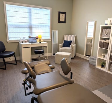 Professional pelvic floor physical therapy clinic room with a treatment table, desk, and cozy seating.