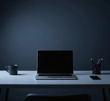A minimalist workspace with a laptop displaying a clean website design in deep navy and ice blue tones.