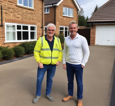 Two men standing on a newly installed resin driveway in front of a modern brick house.