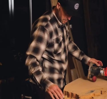 Basile in a plaid shirt and a hat is making a Mended Heart