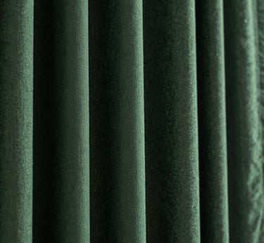 Macro close-up of heavy hunter green curtain fabric texture with deep folds and dramatic side lighting, 35mm