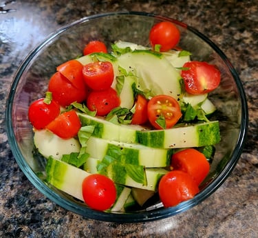 a bowl of cucumbers and tomatoes on a counter