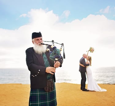 couple kissing on bluff at Sunset Cliffs with bagpiper in forground