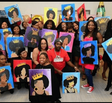 A group of people posing with their finished afro queen paintings at a paint and sip event.