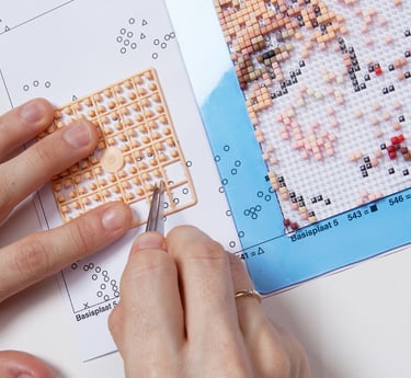 Human creating a picture by using tweezers, transparent baseplate and colorful pixel squares