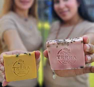 two women holding soap bars in front of a table