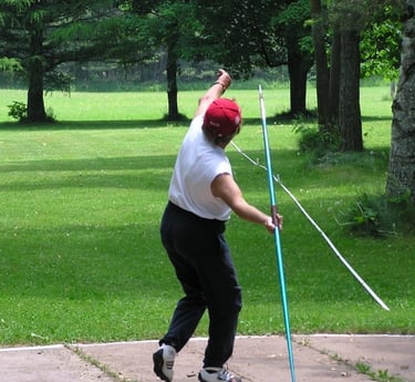 Masters athlete prepares to launch a javelin during outdoor competition, with arm extended and focus