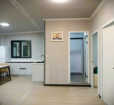 Modern prefab container home interior with white kitchen, dining area, and neutral walls.