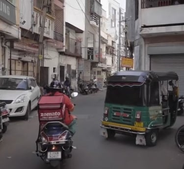 a zomato rider riding a motorcycle down a street