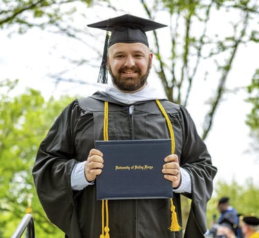 a man in a graduation gown holding a diploma
