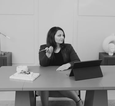 Professional businesswoman sitting at a modern office desk using a smartphone for work.