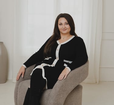 Adriana in black and white cardigan dress sits in a modern swivel chair for a professional portrait.