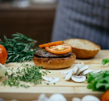 chef making a delicious burger with beef, tomato, mushrooms and onions.