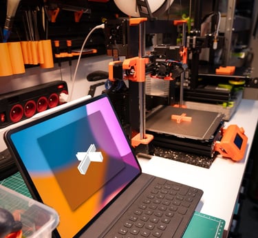 A modern tablet with keyboard on a workbench next to an active 3D printer in a maker workspace.