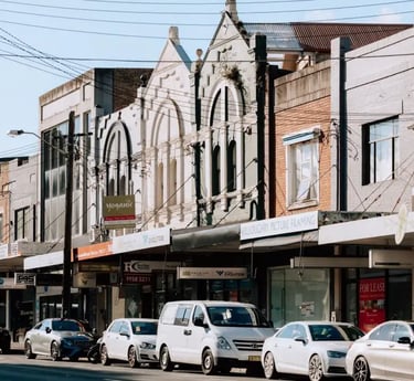 Willoughby storefronts and parked cars on a sunny suburban Sydney street in Willoughby.