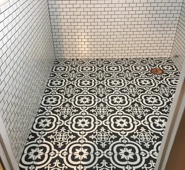 Black and white patterned floor tile installed in a half bathroom with white subway tile walls.