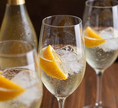 foto cercana de copas servidas detalle de botella, espumante, hielo, frutas o garnish 