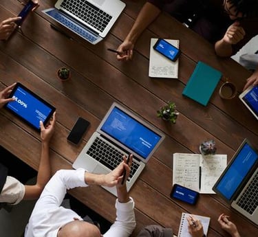 Vista aérea de un equipo empresarial diverso que utiliza computadoras portátiles y tabletas.