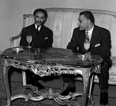 Haile Selassie and Gamal Abdel Nasser meeting in a formal room sitting at a marble table.