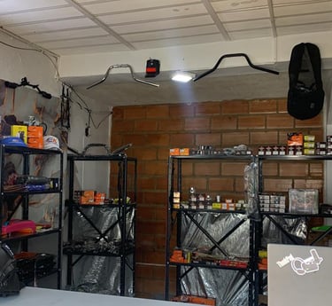 Repuestos y accesorios para motocicletas exhibidos en estanterías metálicas dentro de un taller