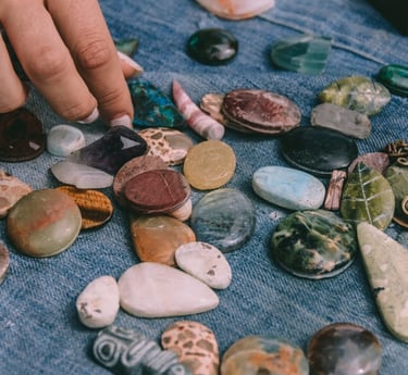 Seleccionando a mano piedras preciosas pulidas, cristales y colgantes de piedra sobre tela de mezcli