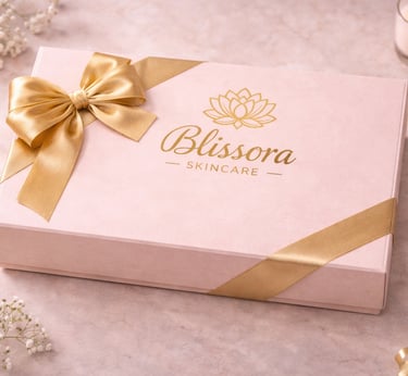 Blissora Skincare elegant pink gift box with a gold ribbon bow on a marble surface.