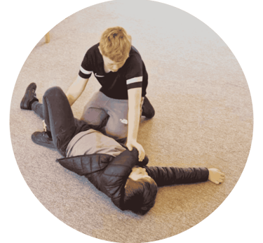 a boy placing another boy into the recovery position during a Frist Aid workshop