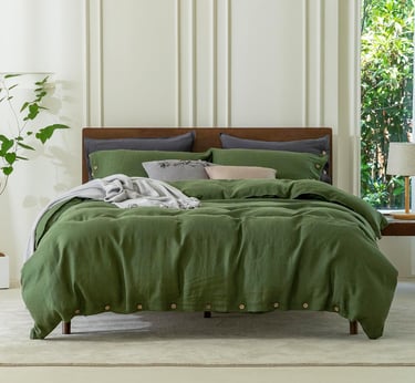 Green linen duvet cover set on a wooden bed frame in a bright modern bedroom.