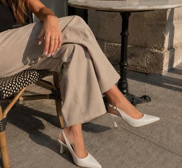 Woman wearing white pointed toe slingback heels.
