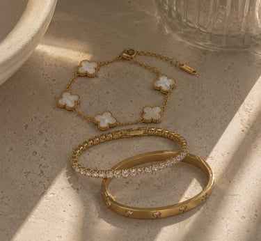 Minimalist gold bracelets with clover detail.
