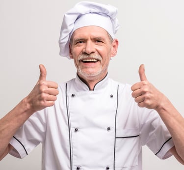 a chef in a white chef's uniform with thumbs up
