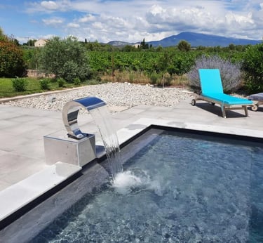 Piscine de luxe avec cascade moderne en acier inoxydable et vue sur les vignes.