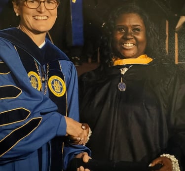 A smiling Spalding University graduate receives her diploma during a formal commencement ceremony.