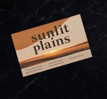 Business card with “Sunlit Plains” branding sits on polished black marble benchtop