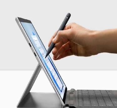 a person's hand holding a pen and writing on a laptop