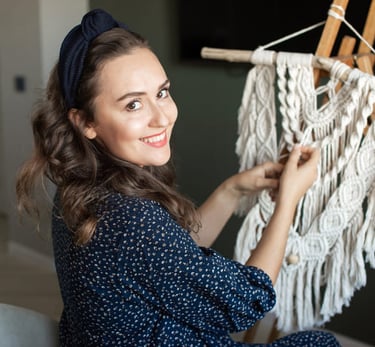 Mujer sonriente creando un tapiz de macramé blanco en su estudio.