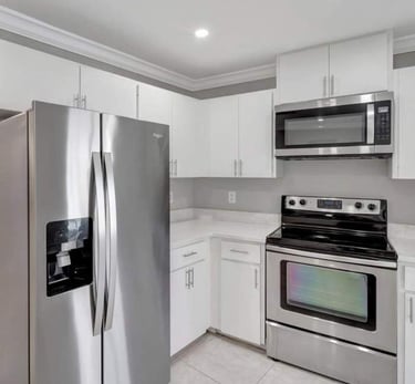 Kitchen remodel with white cabinets and stainless steel refrigerator, microwave, and oven.