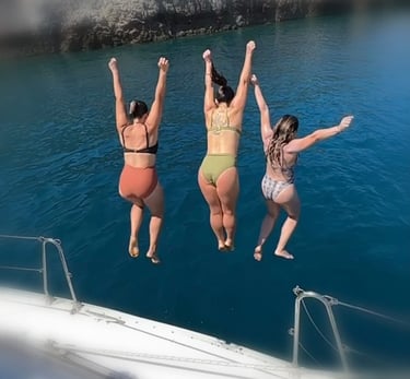three women jumping into the sea in chania in a boat
