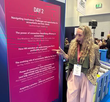a woman standing in front of a sign that says Elysian Services HR Ltd speaker slot at Accountex