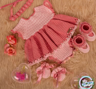 Handmade pink crochet baby girl dress set with matching shoes, headband, and mittens on a fur background.