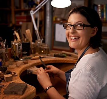 Mujer sonriente trabajando en joyería en un estudio de trabajo