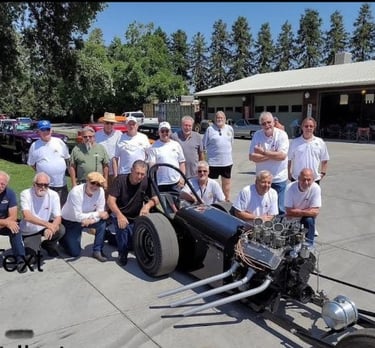 Visalia Vapor Trailers Car club members posing with the club tribute dragster
