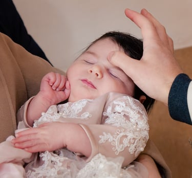 majka drži bebu u svojim rukama za vrijeme obreda krštenja