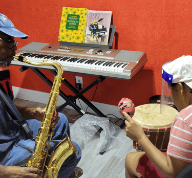a man playing a saxophone and a woman playing playing a drum and shaking a maraca