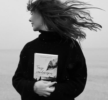a woman standing on a beach holding a book
