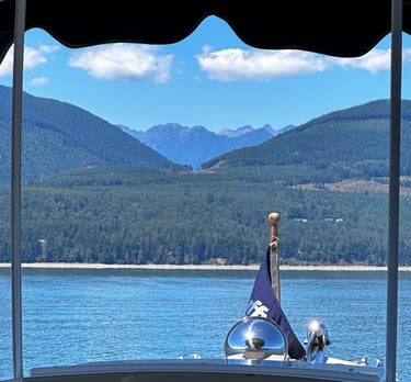 front of boat with flag on pristine water facing majestic mountains