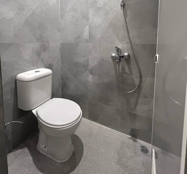 Kamar mandi dalam kos dengan shower, toilet duduk, dan water heater di Kos Si Bos Surabaya