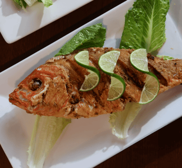 a plate of fried fish trout garnish with lemon slices